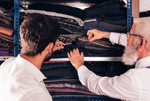 close-up-man-male-senior-tailor-selecting-fabric-shelf_23-2148180337